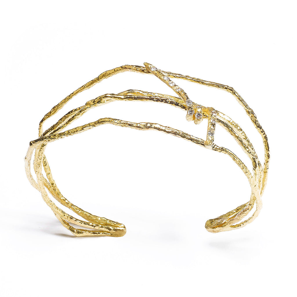 The Under a Tree cuff is a stunning piece that captures the essence of nature's beauty in a statement of elegance and modern style. Crafted from textured 18k yellow gold, this cuff showcases a unique design that exudes both vitality and sophistication. The center element is accented by petite diamonds, adding a bright sparkle that enhances its dynamic appeal. Perfect for those who appreciate fine craftsmanship and distinctive jewelry, the Under a Tree cuff is a must-have accessory.  