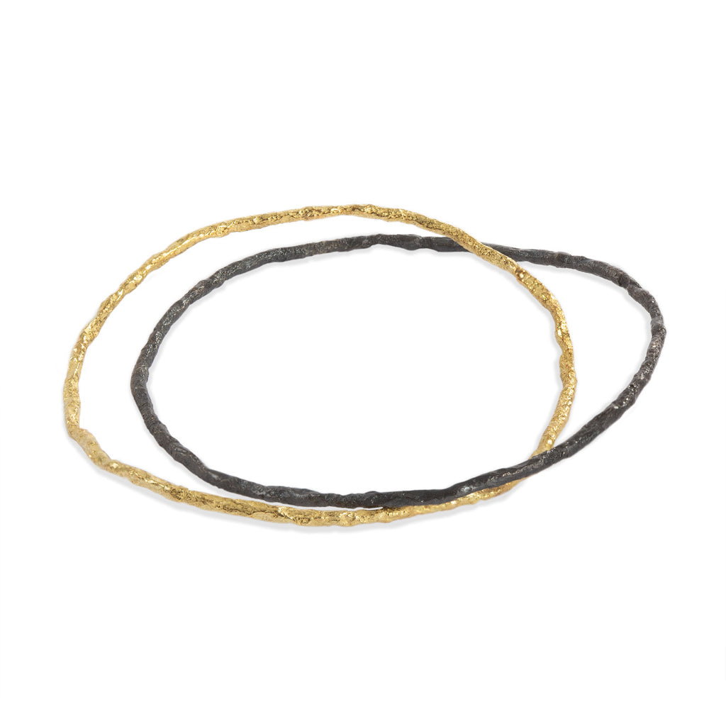 This Svelare bangles, fashioned from 18k yellow gold and blackened sterling silver, elegantly entwine with each other, creating a captivating and harmonious design.